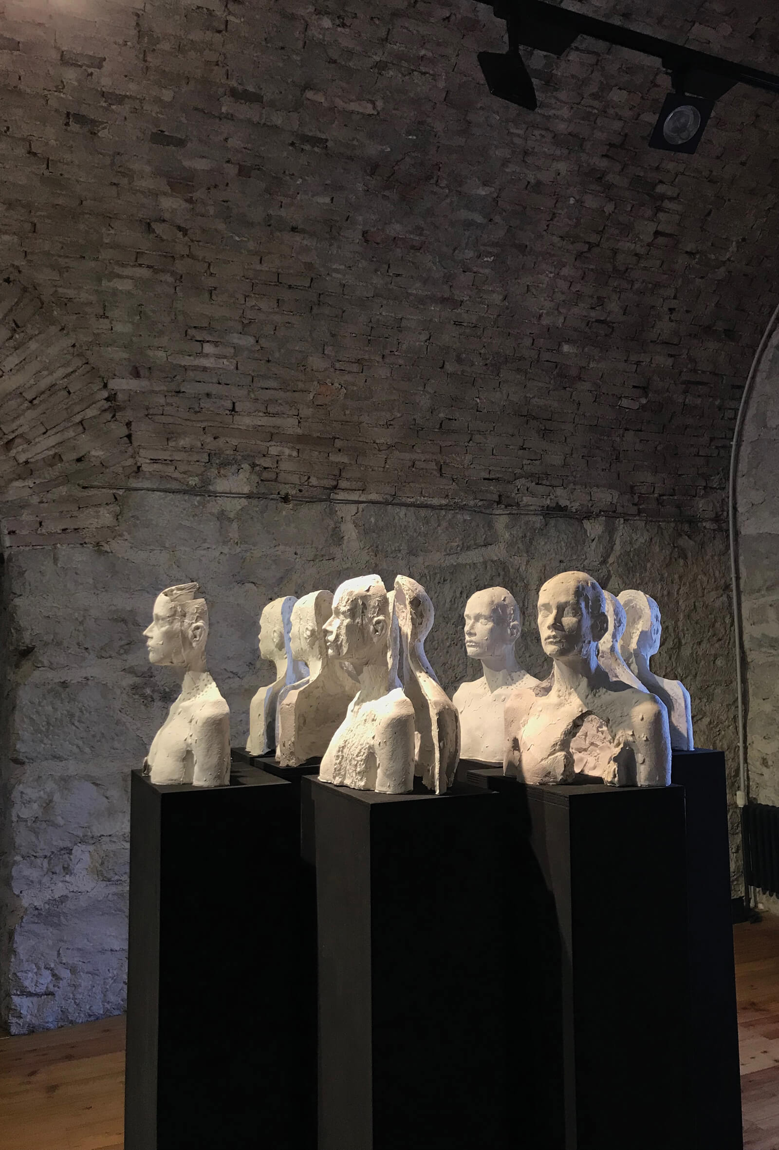 laura marcolini, installazione artistica composta di tredici busti di donna consunti ed erosi, in gesso bianco e colonne di sostegno scure, opera della scultrice trentina Laura Marcolini, dal titolo 