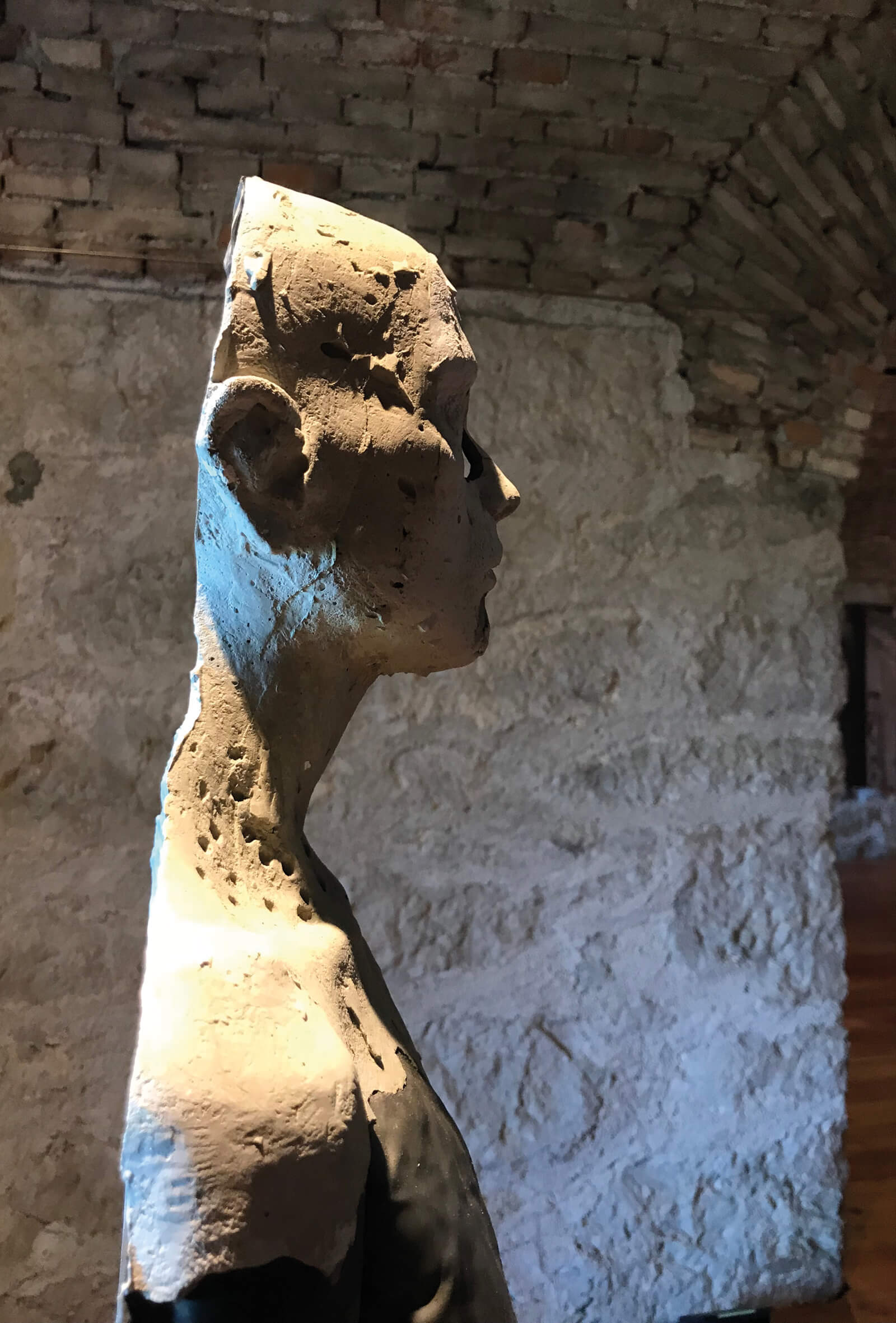 dettaglio di una scultura in cemento raffigurante un profilo di donna scavato e consunto, con inserti in metallo, dell'artista trentina Laura Marcolini, esposta in occasione della mostra Fragile, al forte superiore di nago, anno 2021.